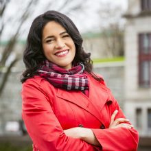 Saroja Coelho outside wearing a red jacket.